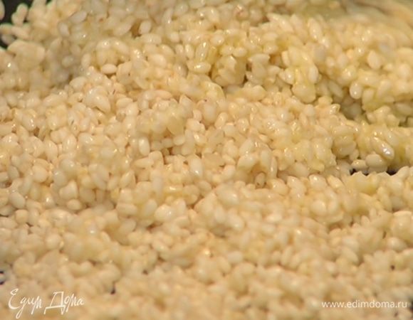 Всыпать к луку рис и, постоянно помешивая, обжаривать около 1 минуты.