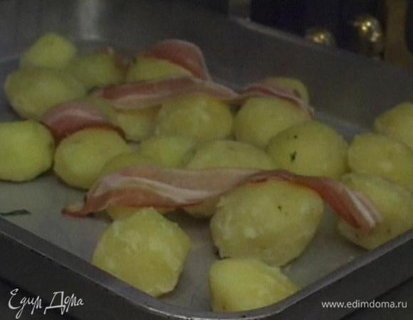 Вынуть противень из духовки, выложить в него картофель, сверху разложить кусочки бекона, затем вернуть противень с картошкой на нижний уровень духовки и продолжать запекать все еще 40‒45 минут.