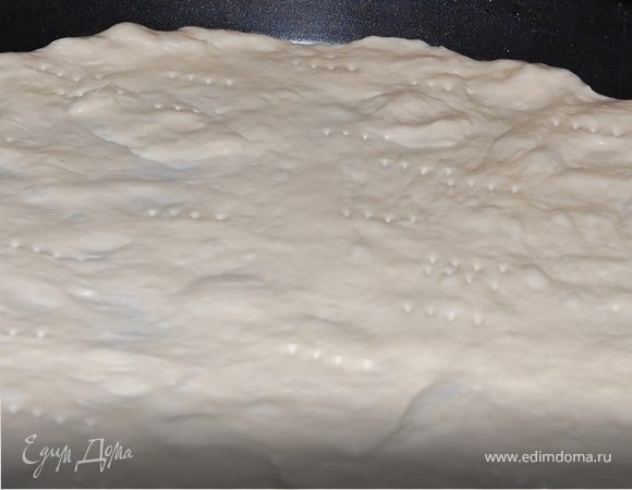 Подошедшее тесто разделите на две части.
Распределите руками тесто на круглой форме,достаточно тонко, мм3-4.Наколите его вилкой,по всему диаметру.