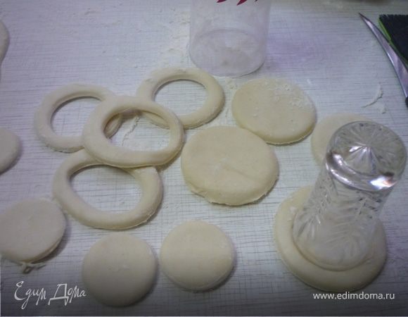 Слоеное тесто не раскатываем, присыпаем стол слегка мукой, разворачиваем размороженное тесто, вырезаем большие круги диаметром 8 см. Внутри большого круга вырезаем круг поменьше.
