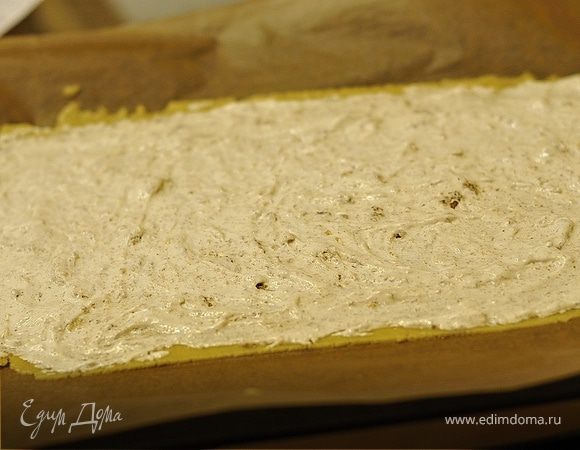 4)Достать шарик теста из холодильника и раскатать на бумаге для выпечки пласт прямоугольной формы. Сверху смазать его белковой массой.