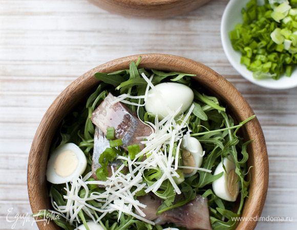 Выложить салат на большую тарелку, сверху разложить половинки яиц и кусочки сельди. Посыпать зеленым луком и натертым сыром.