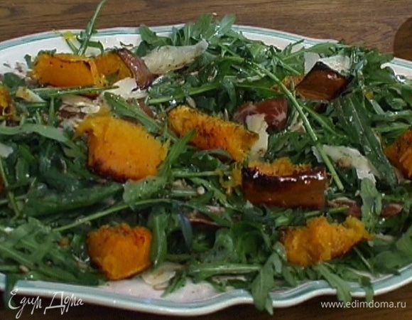Уложить руколу на большое блюдо, полить половиной заправки, сверху выложить ветчину и кусочки запеченной тыквы, присыпать натертым сыром и поджаренными семечками.