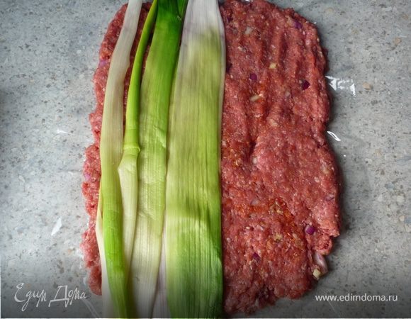 Фарш выложить на пищевую пленку в виде прямоугольника толщиной 1см. На фарш выложить лук-порей.