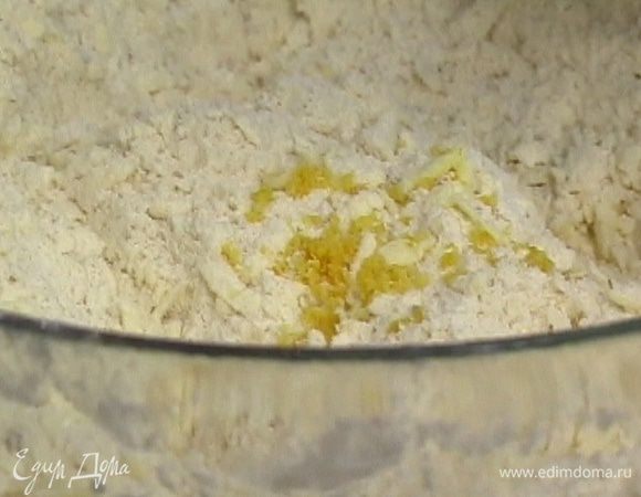 Предварительно замороженное сливочное масло натереть на крупной терке и выложить к муке. Добавить цедру лимона, желток и яйцо, перемешать.