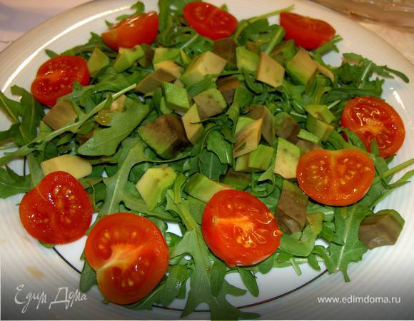 Выложите авокадо на рукколу, добавьте половинки черри.
