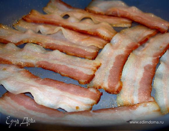 Длинные тонкие ломтики бекона поджарим на слабом огне до прозрачности.