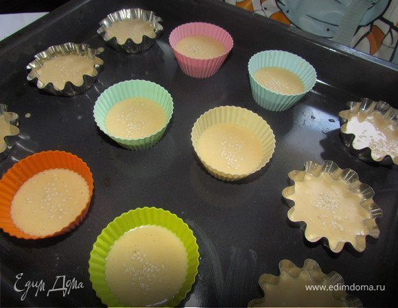 Нагреваем духовку до 230С. Формочки тоже должны быть теплыми, для этого их надо поставить на минутку в разогретую духовку. Если у Вас формочки силиконовые, то их не надо смазывать, если другие,  то их надо смазать маслом. В теплые формочки наливаем на 1/2 наше тесто, присыпаем немного кунжутом и отправляем в хорошо разогретую духовку. 