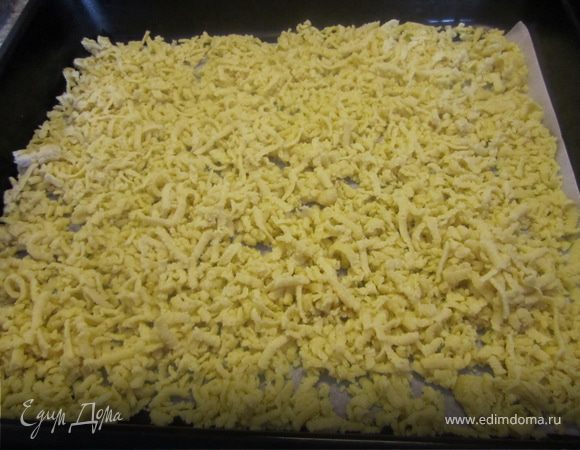 Духовку включить на 180 гр.
Форму застелить пергаментом.
Одну часть теста достать из морозилке, натерель на купной терке, разровнять по форме.