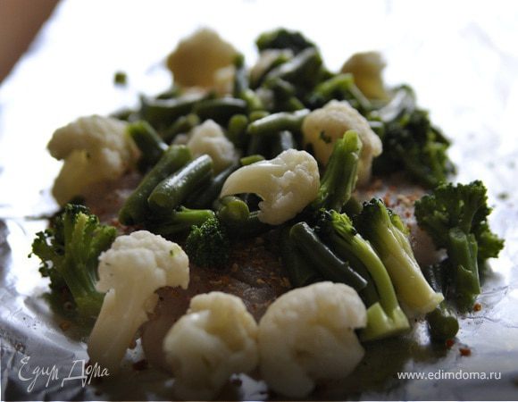 Размороженные овощи, приправляем солью и перцем и выкладываем на рыбу.