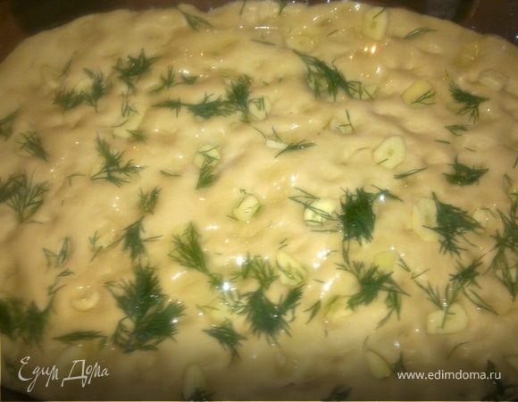 Затем тесто на противне сбрызнуть оливковым масло.Сверху выложить нарезанные клечками дольки чеснока(побольше),немного вдавливая в тесто,посыпаем порваной руками зеленью укропа и немного присаливаем сверху.Ставим в духовку на 20-30 минут.