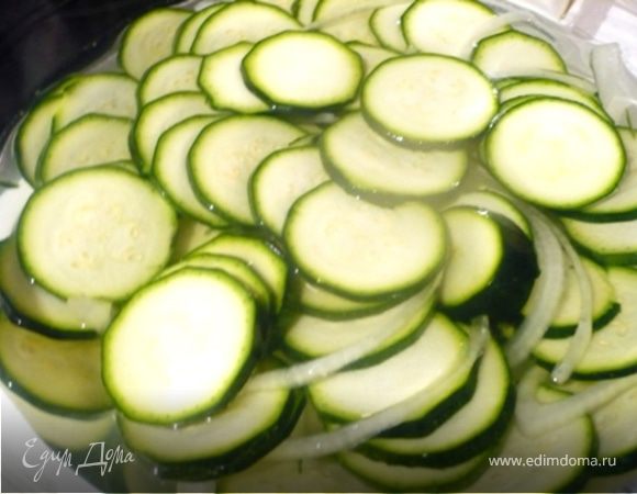 Цукини и лук сложить в стеклянную посуда, посыпать солью и залить 250 мл. холодной воды из холодильника. Перемешать, чтобы соль растворилась и оставить на 1 час, пока цукини не размякнут. 

