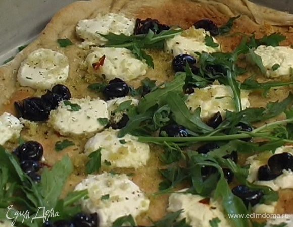 Готовую пиццу посыпать измельченными листьями базилика, руколой, сбрызнуть оставшимся оливковым маслом и лимонным соком.