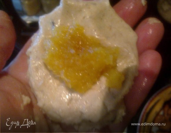 Берем из холодильника нашу песочно -кремовую массу.Руки опускаем в воду,берем мокрыми руками порцию смеси,кладем на ладошку лепешкой,на лепешку целый миндальный орешек,затем глазированую мякоть апельсина.Формуем шарик,чтоб начинка осталась внутри.