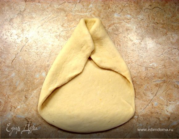 Теперь левой рукой берем левый край теста и натягиваем на предыдущую складочку…