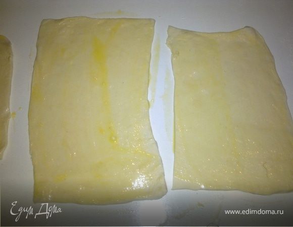 Взбить один желток венчиком и смазать кулинарной кисточкой прямоугольники из теста.