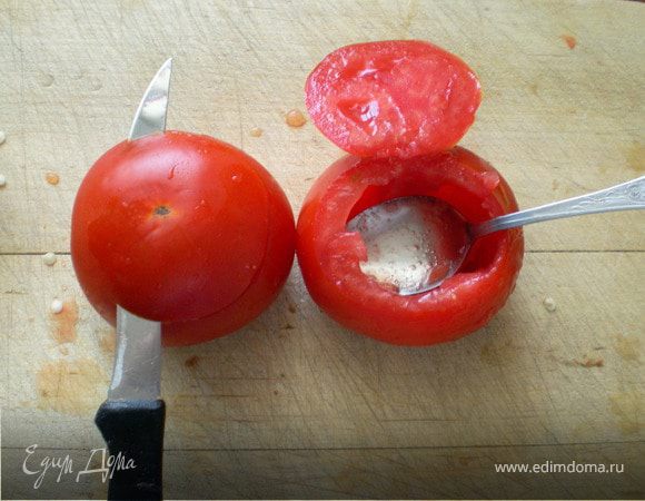 Отрезать но не до конца нижнюю часть помидора,потому что она мягче верхней( чтобы во время варки не лопнула и не рассыпалась).Мякоть помидора вырезать в начале ножом,а потом вычистить чайной ложкой.Мякоть не выбрасывать оставить для соуса.