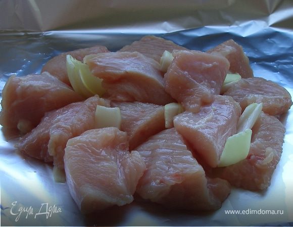 Форму застелить фольгой. Выложить на нее порезанные лук и филе индейки. 