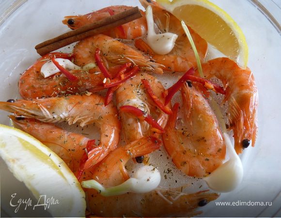 Креветки выложить в блюдо для запекания вместе с дольками лимона, зубчиками чеснока, корицей, перцем чили, сбрызнуть оливковым маслом. Запекать в духовке 180гр. 30мин.
