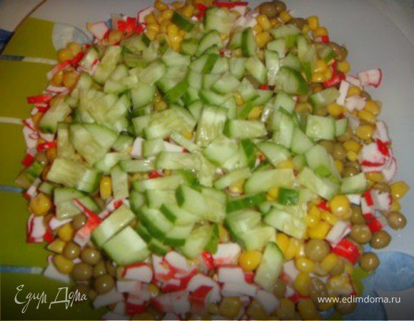 Рис ставим варится. И пока он варится мы режем мелко крабовые палочки, огурец. Высыпаем горох и кукурузу.