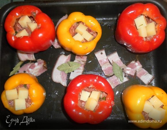 1. У перчика срезаем верхушку, чистим от зёрен, хорошо промываем. Смазываем изнутри оливковым маслом и морской солью.
2. Варим рис до полуготовности, промываем холодной водой и даём ей полностью стечь.
3. ГОТОВИМ ФАРШ: обжариваем мелко нарезанную луковицу на оливковом масле до золотистого цвета, добавляем томатную пасту и с открытой крышкой пассируем на большом огне 2-3 минуты,постоянно помешивая. Хорошо перемешиваем фарш с получившейся массой и рисом. Добавляем мелко порубленную зелень, солим по вкусу, приправляем розмарином, тимьяном и паприкой (молотая приправка). 
4. Начиняем перчики нашим фаршем, оставляя 1 см. до верхушки. Сверху на каждый кладём по 3 кубика сыра (он начнёт плавится и "запечатает" наши перцы, чтобы фарш не выпал).
5. Выкладываем перцы на смазанный оливковым маслом противень. На дно противня выкладываем нарезанный шпик, лавровый лист и чёрный перец.
