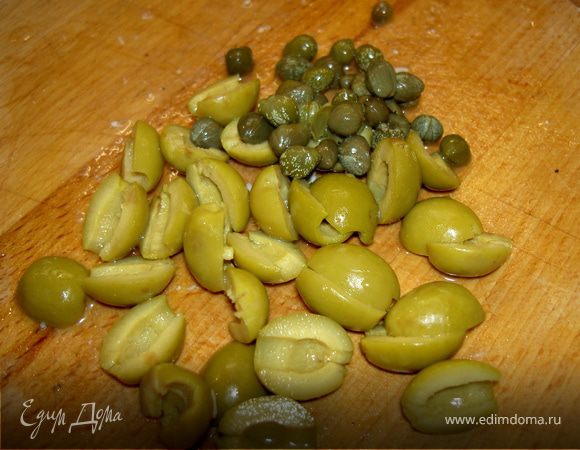  Оливки без косточки разрежьте пополам и добавьте в салат. Присыпьте салат каперсами.