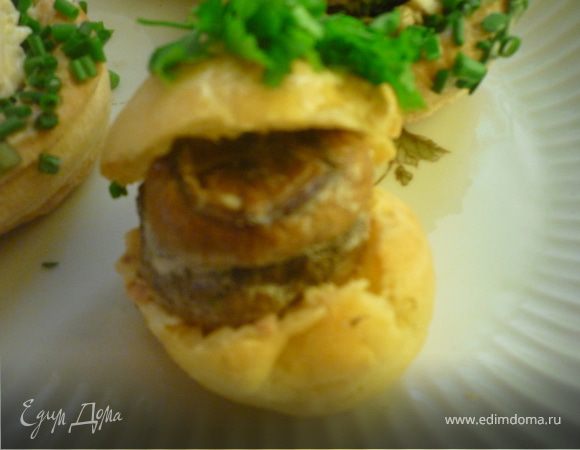 Собираем закуску: профитроли режем пополам, нижнюю часть смазываем начинкой, в центре кладем немного сыра Viola, сверху "грибную черную жемчужину".