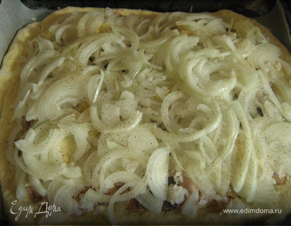 Готовое тесто разделите на 2 части и раскатайте 2 пласта, противень застелите бумагой для выпечки, аккуратно разложите один пласт теста и слоями выложите начинку: рис, рыбу, кусочки сливочного масла и лук. Посолите, поперчите.