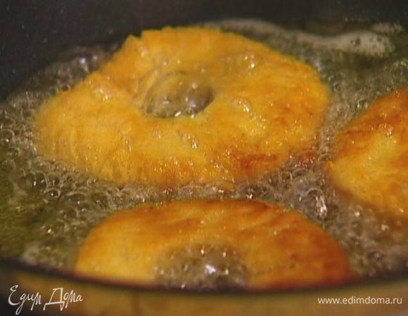 Разогреть в глубокой тяжелой сковороде растительное масло и обжарить пончики с двух сторон.