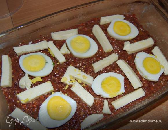 В форму, смазанную маслом (можно использовать любое, я брала сливочное) и присыпанную сухарями, выкладываем половину получившейся смеси, сверху нее - нарезанные половинками вареные яйца,брусочки сыра (любой,у меня домашний),небольшие кусочки сливочного масла.
