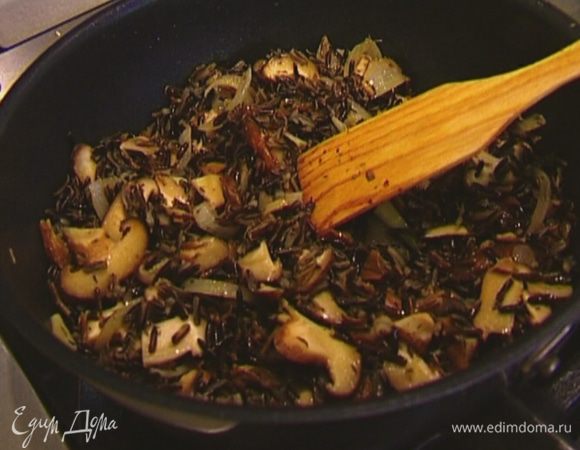 Всыпать рис и перемешать. Если получается суховато, влить еще немного куриного бульона (примерно 2 ст. ложки) и прогревать грибы вместе с рисом несколько минут.