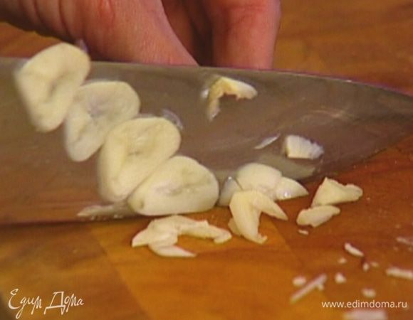 Чеснок почистить, нарезать пластинками и выложить к луку. 