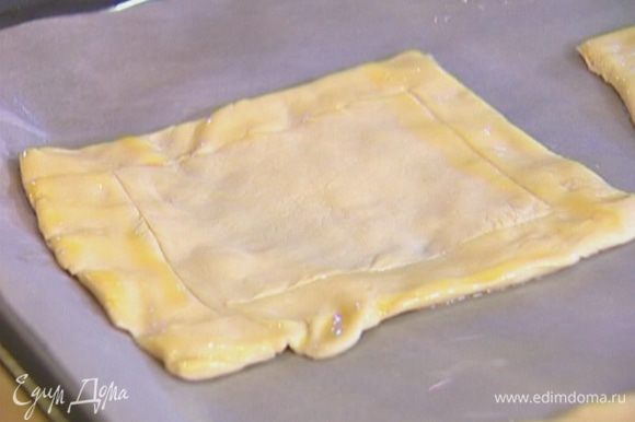 Противень выстелить бумагой для выпечки, смазать ее оливковым маслом и выложить квадратики теста.