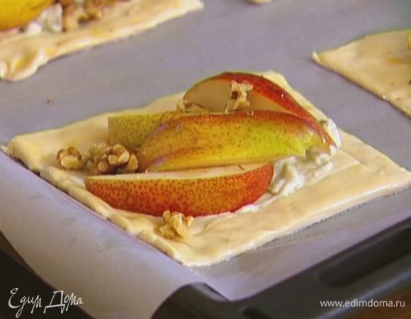 Выложить сырную начинку в центр квадратиков из теста, сверху положить дольки груш, добавить несколько капель кленового сиропа, посыпать орехами, посолить и поперчить.