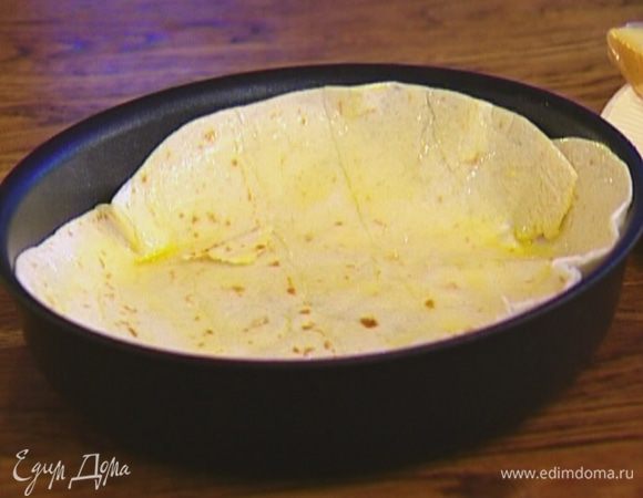 Тортилью выложить на дно сковороды или формы для выпечки, так чтобы получились бортики. Кулинарной кисточкой смазать всю лепешку оливковым маслом.