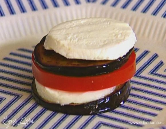 На тарелку выложить обжаренный кружок баклажана, на него поместить ломтик моцареллы, сверху — ломтик помидора, затем снова баклажан, моцареллу и помидор. 