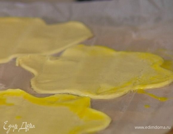 Яйцо взбить, смазать им края вырезанных фигурок и переложить пергамент на противень.