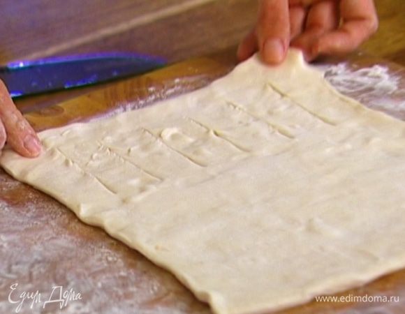 Размороженный пласт теста немного растянуть в стороны руками. Один край (до середины) нарезать полосками шириной 1,5–2 см.