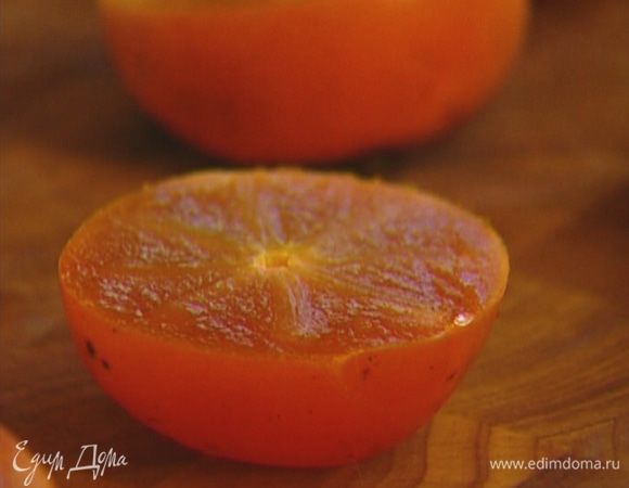 Хурму разрезать пополам и уложить в небольшой противень срезом вверх.