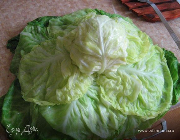 Теперь подготовим капусту. Для этого приварим ее. Подготовьте себе поблизости друшлаг с емкостью, куда будет стекать вода с капусты после очередного приваривания. Итак, сначала опустим в кипяток весь качан. Ложками достанем его и положим в друшлаг. Затем переместим на доску и аккуратно, последовательно разберем по листьям словно цветочек аленький (в нашем случае - зеленый) не отрывая при этом лепестки.