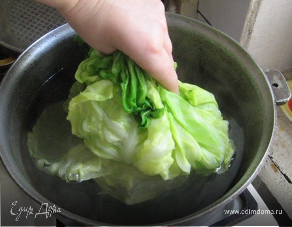 Затем, чтобы приварить оставшийся качан, аккуратно перевернем капустину, возьмем в пучек за развернутые листья и опять опустим в кипяток. Также аккуратно достанем и положим в друшлаг для стекания.