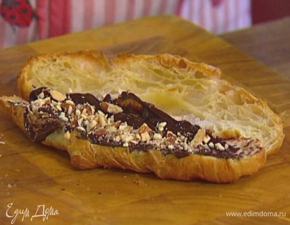 Раскрыть горячие круассаны, намазать шоколадным сыром и посыпать орехами.