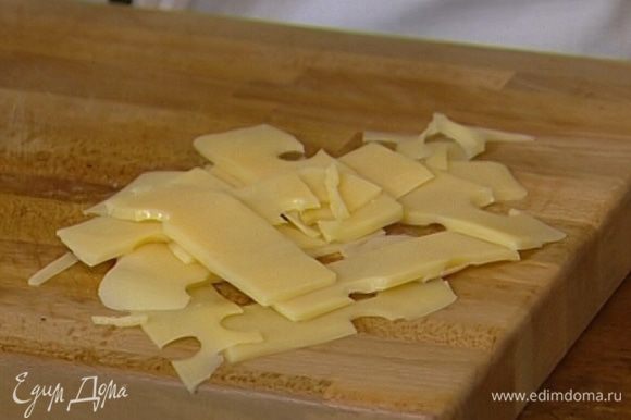 Сыр нарезать тонкими пластинками и вместе с беконом выложить на салат.