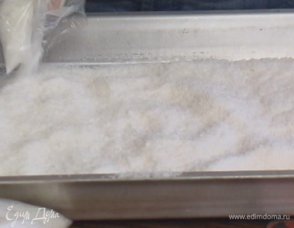 Половину соли высыпать на большой противень.