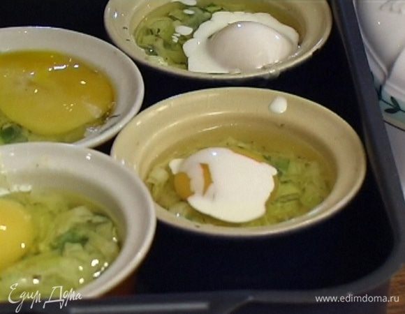 В небольшие формочки для выпекания выложить по 3 ст. ложки луковой смеси, влить по одному яйцу и по 1 ст. ложке сливок.