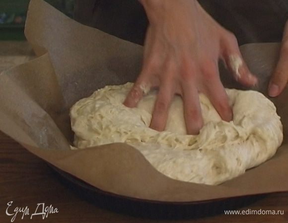 Застелить круглую форму бумагой для выпечки, смазать ее оливковым маслом. Из теста сделать плоскую лепешку, уложить ее в форму.