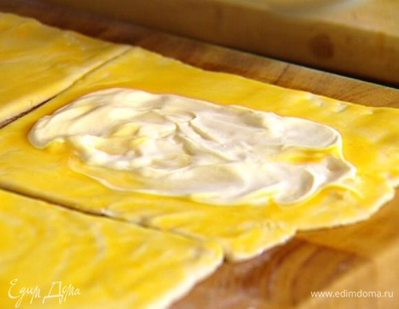 На каждый квадрат выложить ложку сметаны и распределить ее по центру, так чтобы получился круг. 