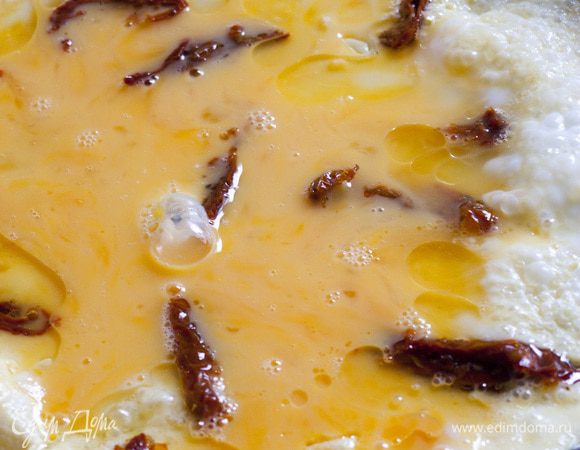 Разогреть в сковороде оливковое масло, влить яичную массу с помидорами, накрыть крышкой, подождать, пока омлет схватится.