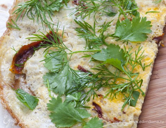 Готовый омлет разрезать пополам или на несколько частей, уложить на лаваш, посыпать листьями петрушки и свернуть в небольшие рулеты.