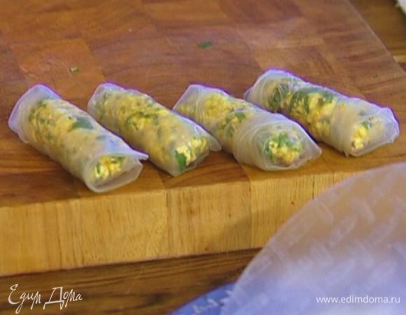 В глубокую посуду налить горячую воду, опустить на несколько секунд рисовую бумагу, затем выложить на чистое полотенце. На край каждого листа положить немного начинки и свернуть конвертиками.